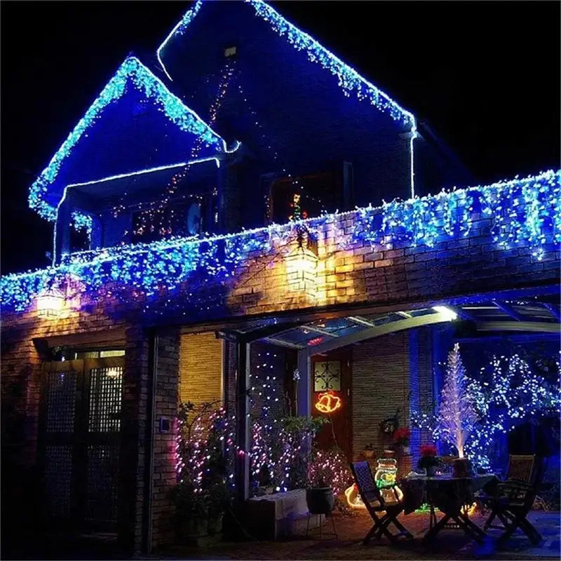 Blue led outdoor christmas waterfall curtain string lights decorate the roofline and balcony of a brick house at night