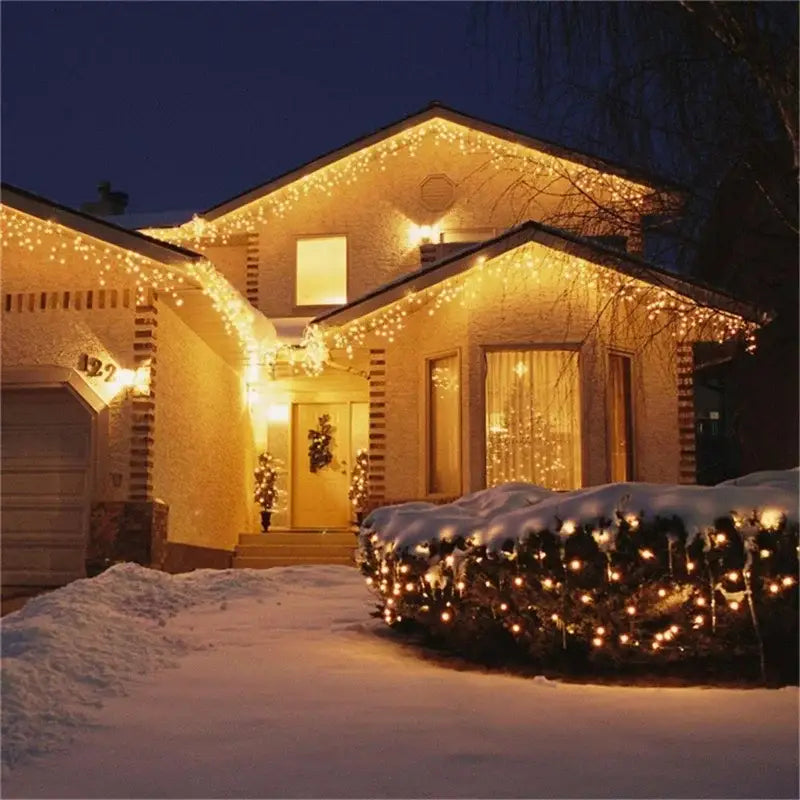 Warm white decorbites™ outdoor christmas waterfall curtain string lights draped on eaves and snow-covered bushes