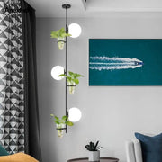 DecorBites pendant planter light featuring black metal frame, three white spherical bulbs, and glass planters with green foliage