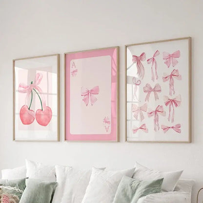 Three framed pink bows wall art set with cherries and playing cards prints displayed above a bed by DecorBites™