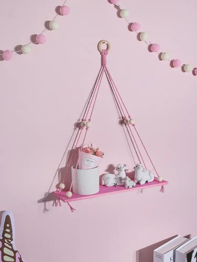 Pink green wooden macrame hanging shelf with wooden ring tassels holding white ceramic pot and miniature sheep for kids room