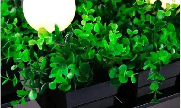 Decorbites™ planter light chandelier features a bright white spherical light nestled in green artificial foliage in a black planter