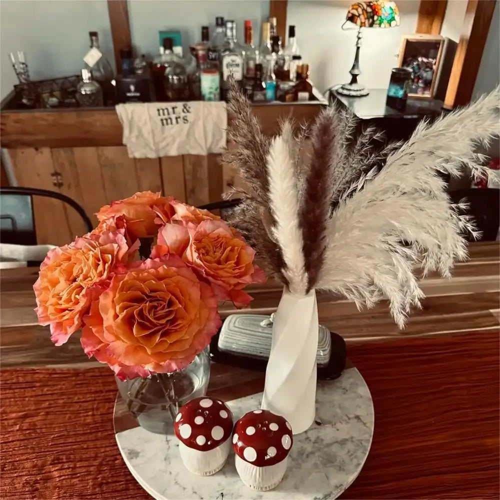 DecorBites™ plastic flower vases feature a white twisted ceramic design holding pampas grass and orange roses
