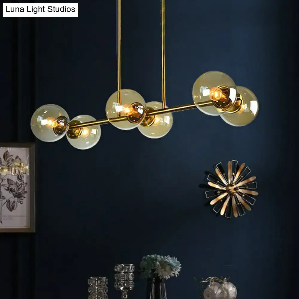 Gold-toned DecorBites™ postmodern brass island light with stylish globe glass shade and frosted glass globe bulbs suspended by rods