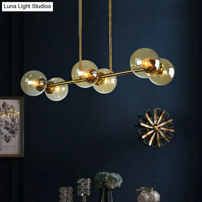 Gold-toned DecorBites™ postmodern brass island light with stylish globe glass shade and frosted glass globe bulbs suspended by rods