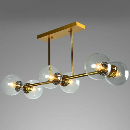 Modern gold-toned brass island light with globe glass shade featuring clear glass globe shades and exposed bulbs
