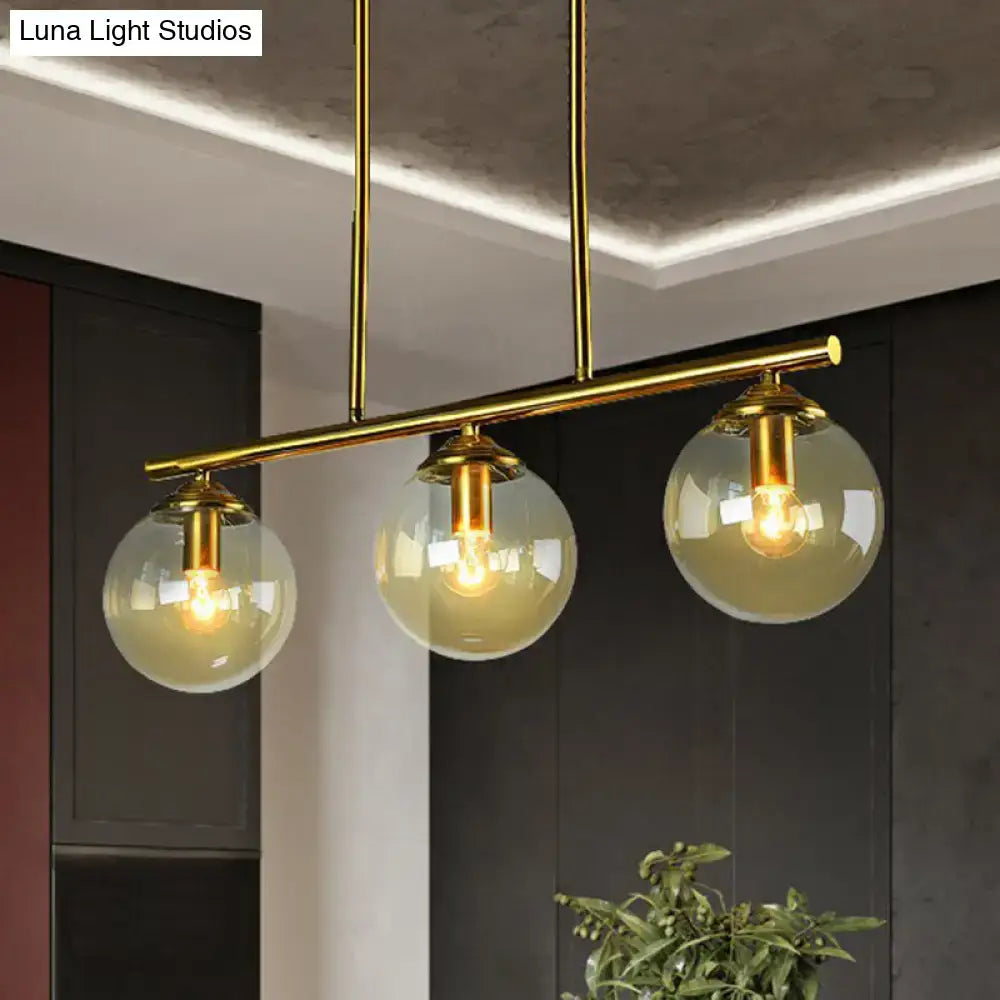 DecorBites postmodern brass island light with gold-toned fixtures and three spherical globe glass shades ceiling fixture
