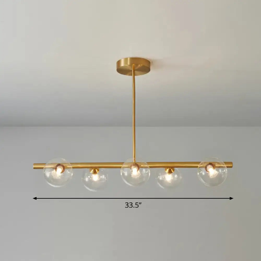 DecorBites postmodern brass pendant light with four clear glass globes and linear island lamp design for dining room
