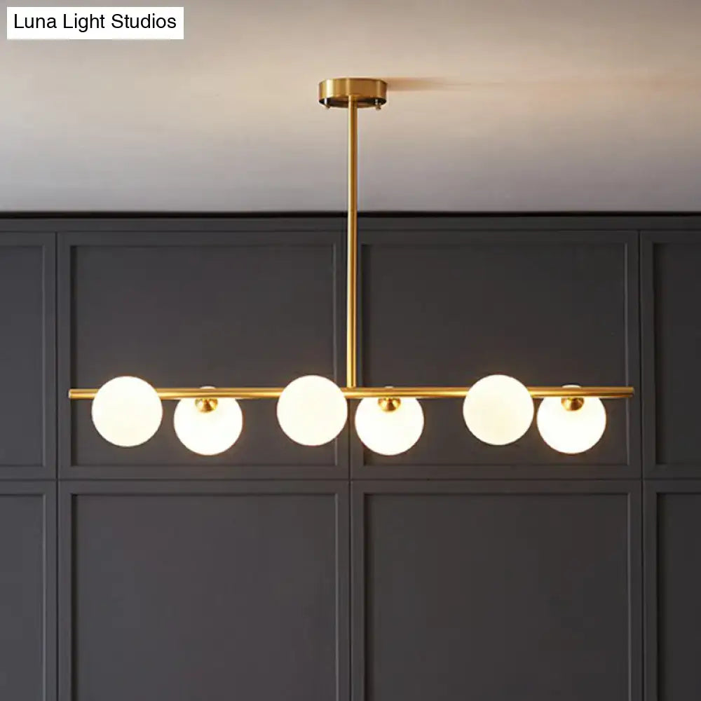 Gold-toned brass linear island lamp pendant light with five frosted glass globes for dining room by DecorBites
