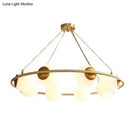 Gold-toned DecorBites™ postmodern metal chandelier with brass finish circular frame and frosted glass globe shades suspended by chains