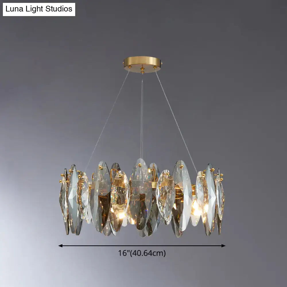 A modern gold chandelier with clear crystal discs complements the postmodern smoke grey glass leaf suspension lamp design