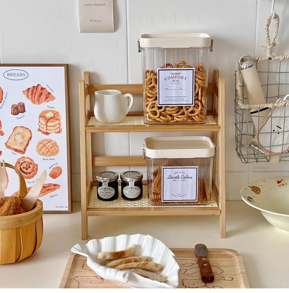 Clear plastic storage containers with cream lids and labels on a rattan 2-tier desktop organizer shelf