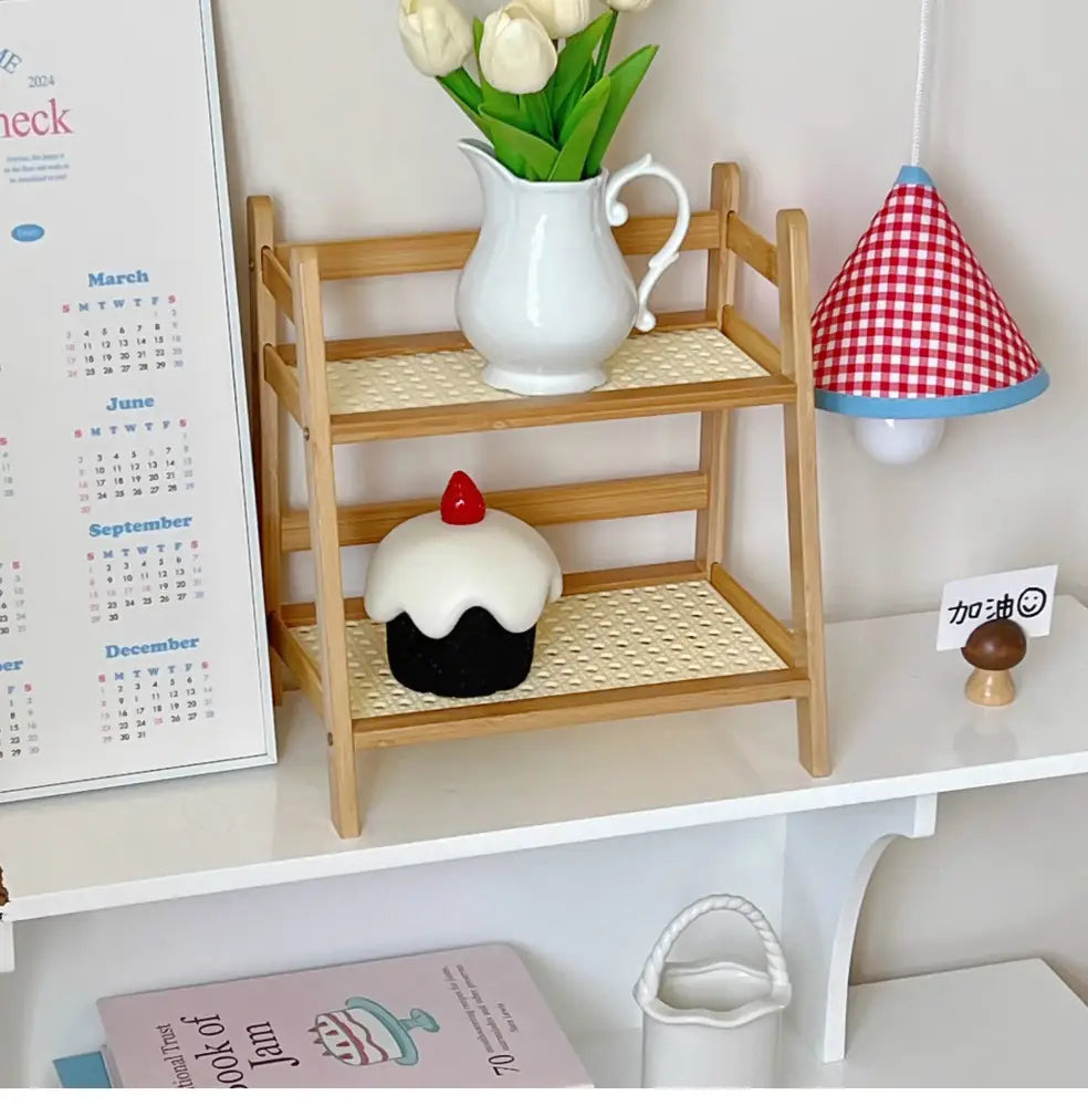 Decorbites™ rattan 2-tier desktop organizer shelf with woven rattan shelves holding a white pitcher and cupcake figurine