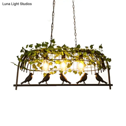 Wrought iron black retro birdcage island light fixture with ivy and bird motifs and warm glowing bulbs