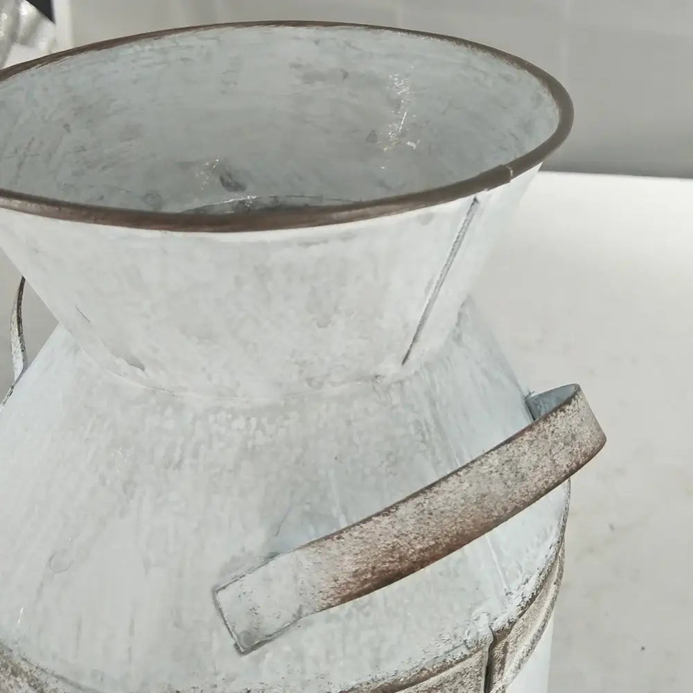 A rustic white galvanized metal vase holder with a weathered finish and sturdy handle for wedding garden decor