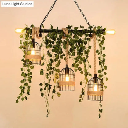 Industrial-style decorbites™ retro metal island light with three black birdcage lamps, rope accents, and hanging green ivy
