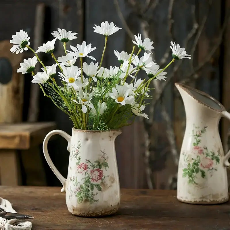 A rustic white ceramic vase with floral pattern and chipped glaze holding fresh daisies in retro nordic ceramic style
