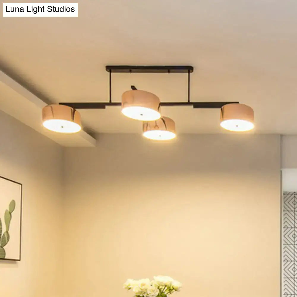 Modern black metal pendant light fixture with four warm-toned cylindrical shades for minimalist dining room