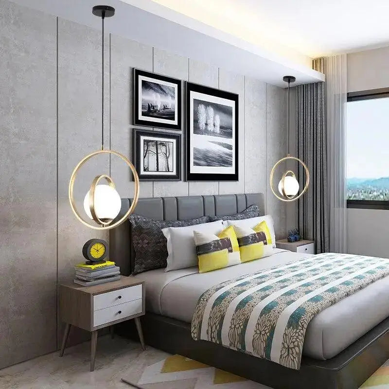 Modern gold-toned rotating gold ring pendant light with frosted glass shades hanging above a bed by decorbites