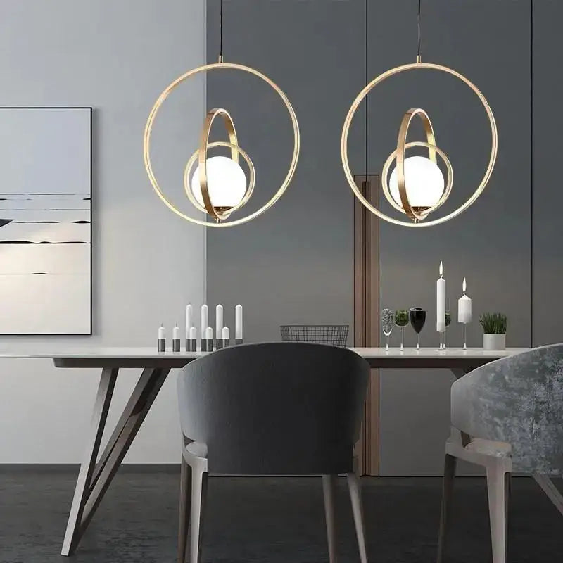 Gold-toned DecorBites™ rotating gold ring pendant light with circular intersecting rings and frosted glass globes