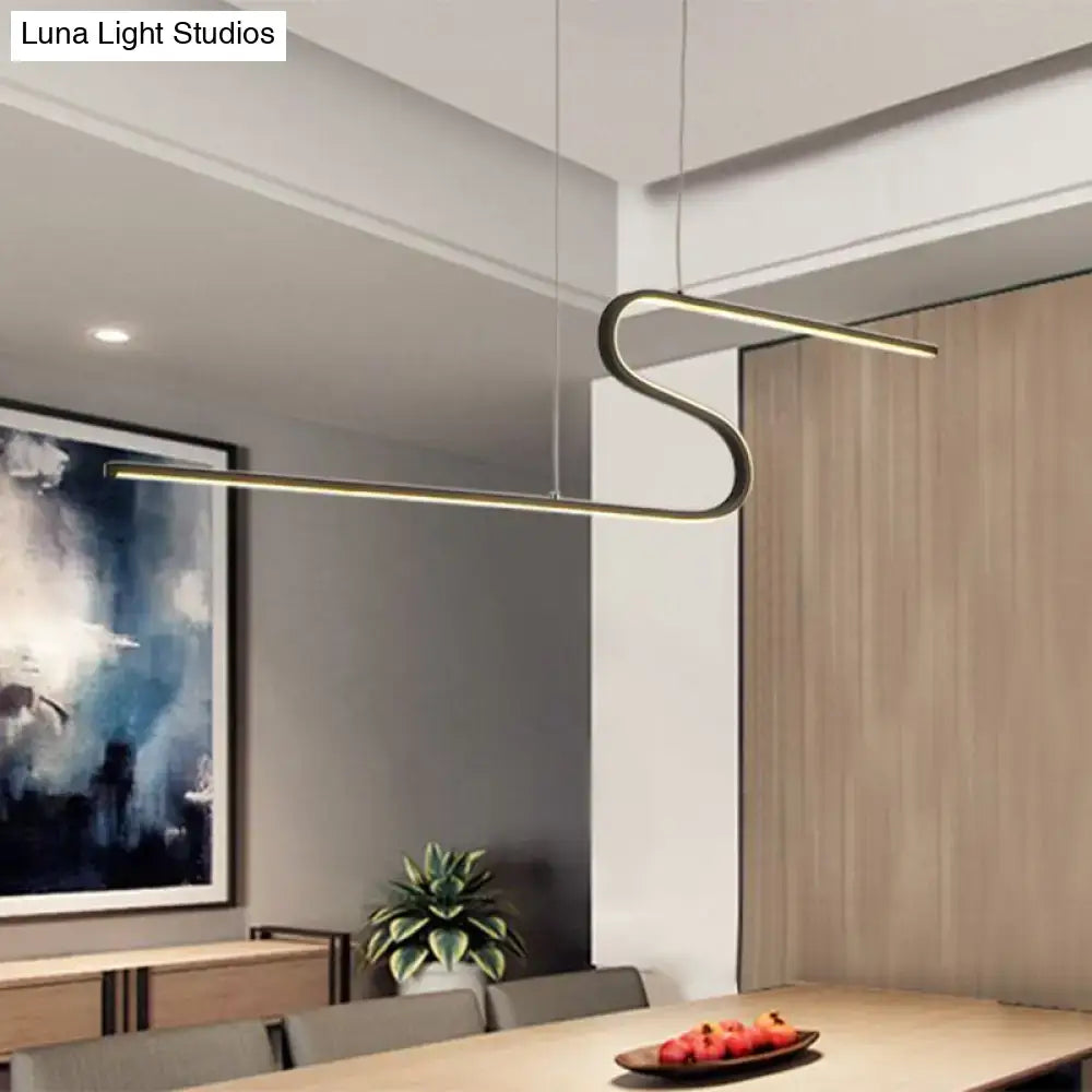 Modern gold-toned decorbites s-shape metal pendant light with warm white light hanging above dining table