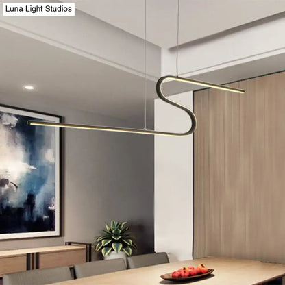 Modern gold-toned decorbites s-shape metal pendant light with warm white light hanging above dining table