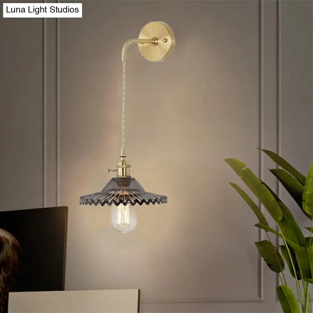 Industrial smoked glass brass sconce light with dark scalloped glass shade and exposed filament bulb for bedroom use