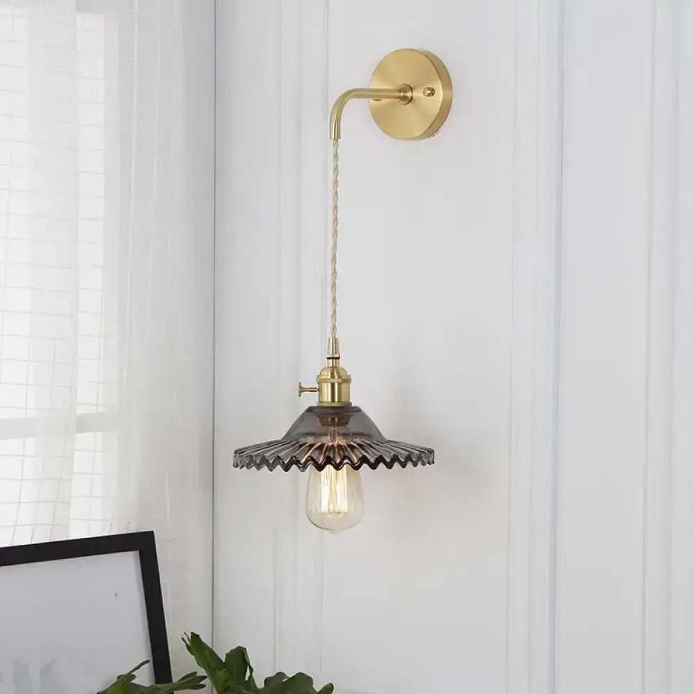 Industrial smoked glass brass sconce light with dark ribbed glass and exposed filament bulb for bedroom use