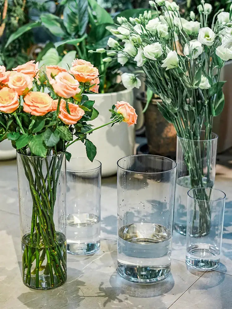 DecorBites™ shatterproof tall transparent acrylic flower vase holding a bouquet of peach-colored roses with green stems
