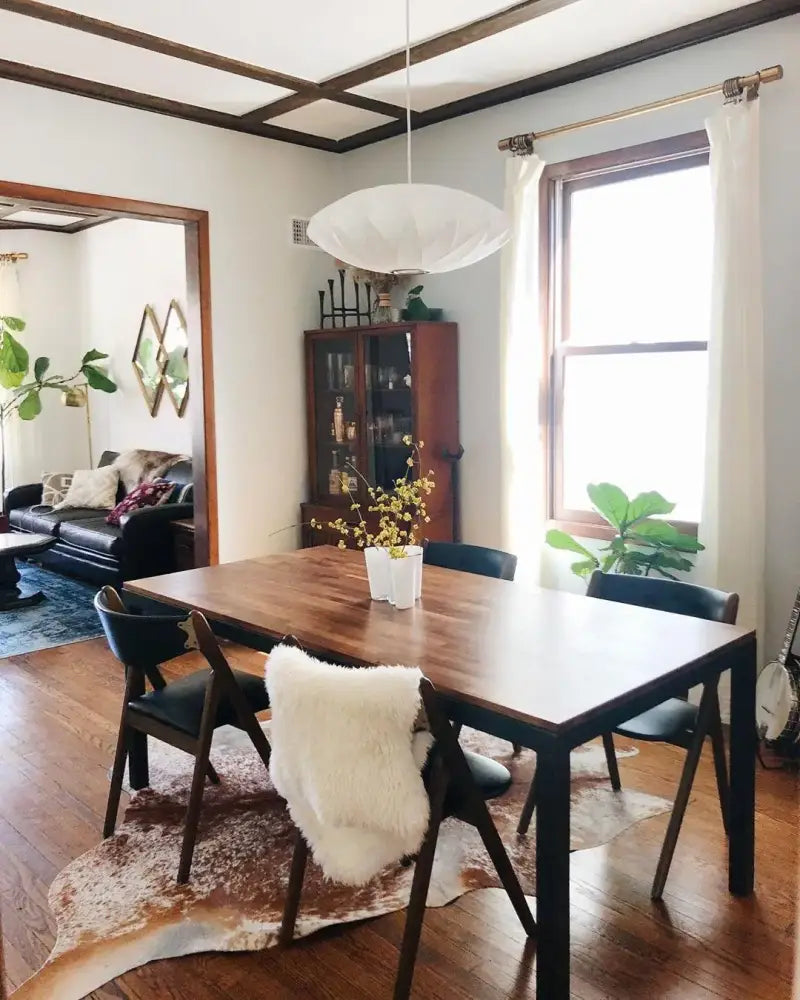 Dark wood dining table with black metal legs and a white fur throw under decorbites silk led pendant lamp modern designer lighting