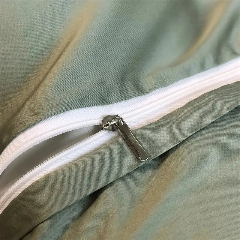 A sleek silver zipper on a eucalyptus fiber duvet cover with white fabric track set against sage green bedding