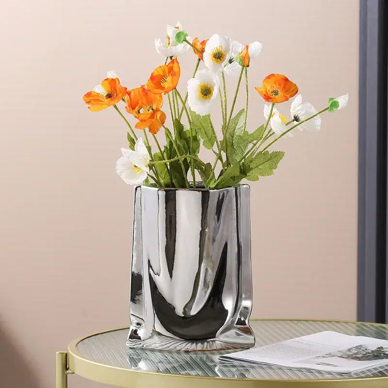 DecorBites silver ruffled flower vase in shiny metallic ceramic holding artificial orange and white poppies