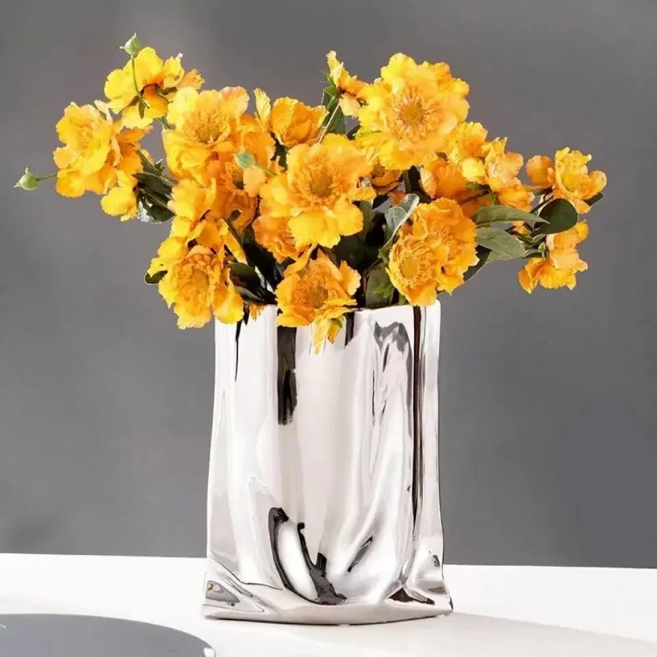 DecorBites™ silver ruffled ceramic flower vase with shiny sculpted design holding vibrant yellow flowers