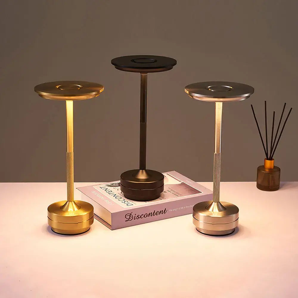 Three modern metallic desk lamps in gold black and silver feature simple charging led and dimming for versatile use