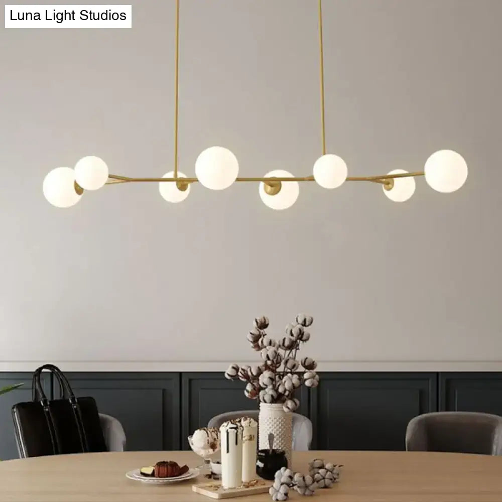 Modern brass pendant light with opal glass globe bulbs in a linear molecular island ceiling design for dining rooms