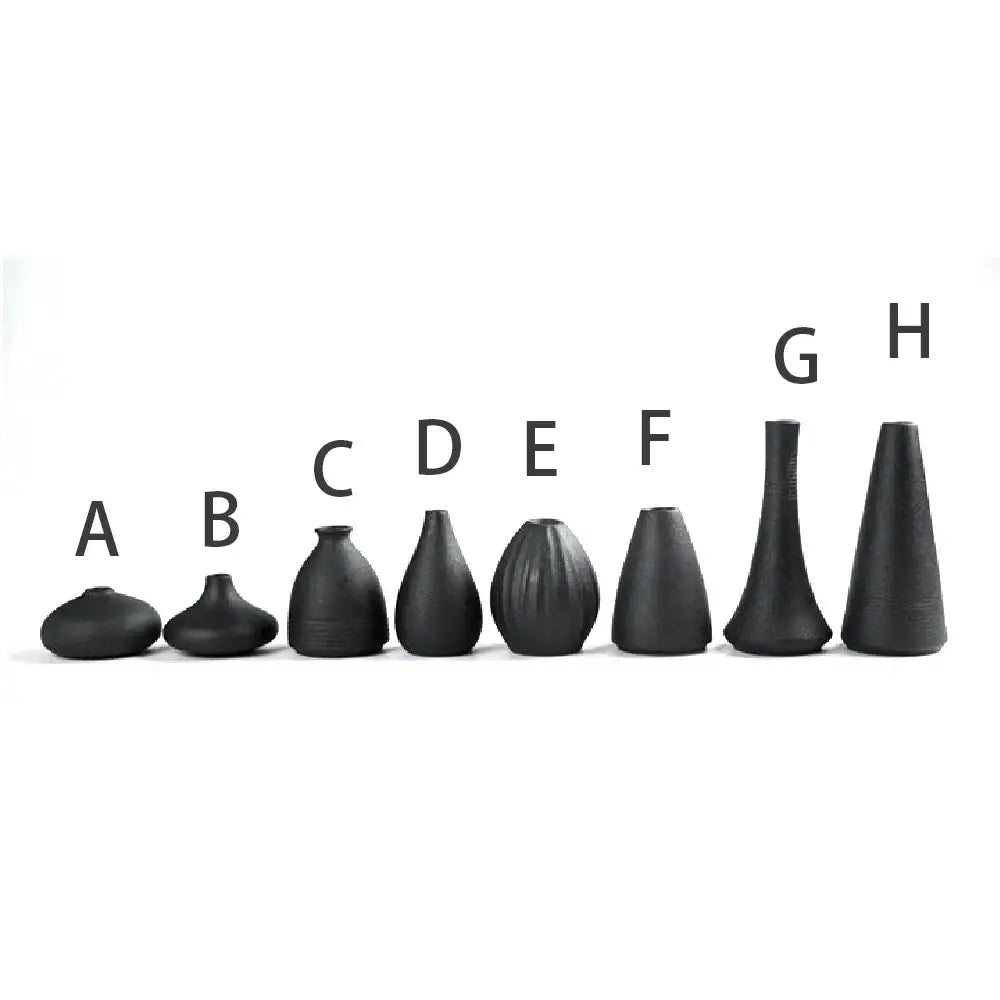 A collection of eight matte black ceramic small vases labeled a to h for elegant japanese home decor by decorbites