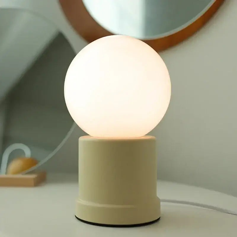 Cream-colored cream-colored small table lamp with spherical matte shade and cylindrical base decorbites bauhaus design