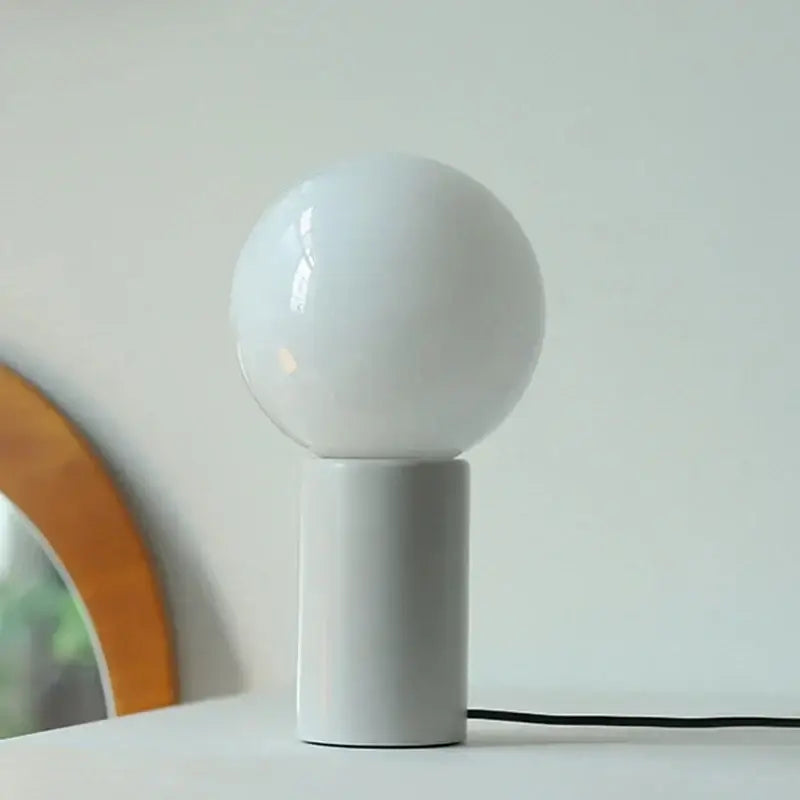 Minimalist white ceramic DecorBites small table lamp with a spherical glass globe on a cylindrical base