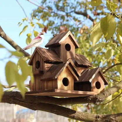 Rustic wooden DecorBites™ small hanging bird house with multiple gabled roofs and circular entry holes on branch