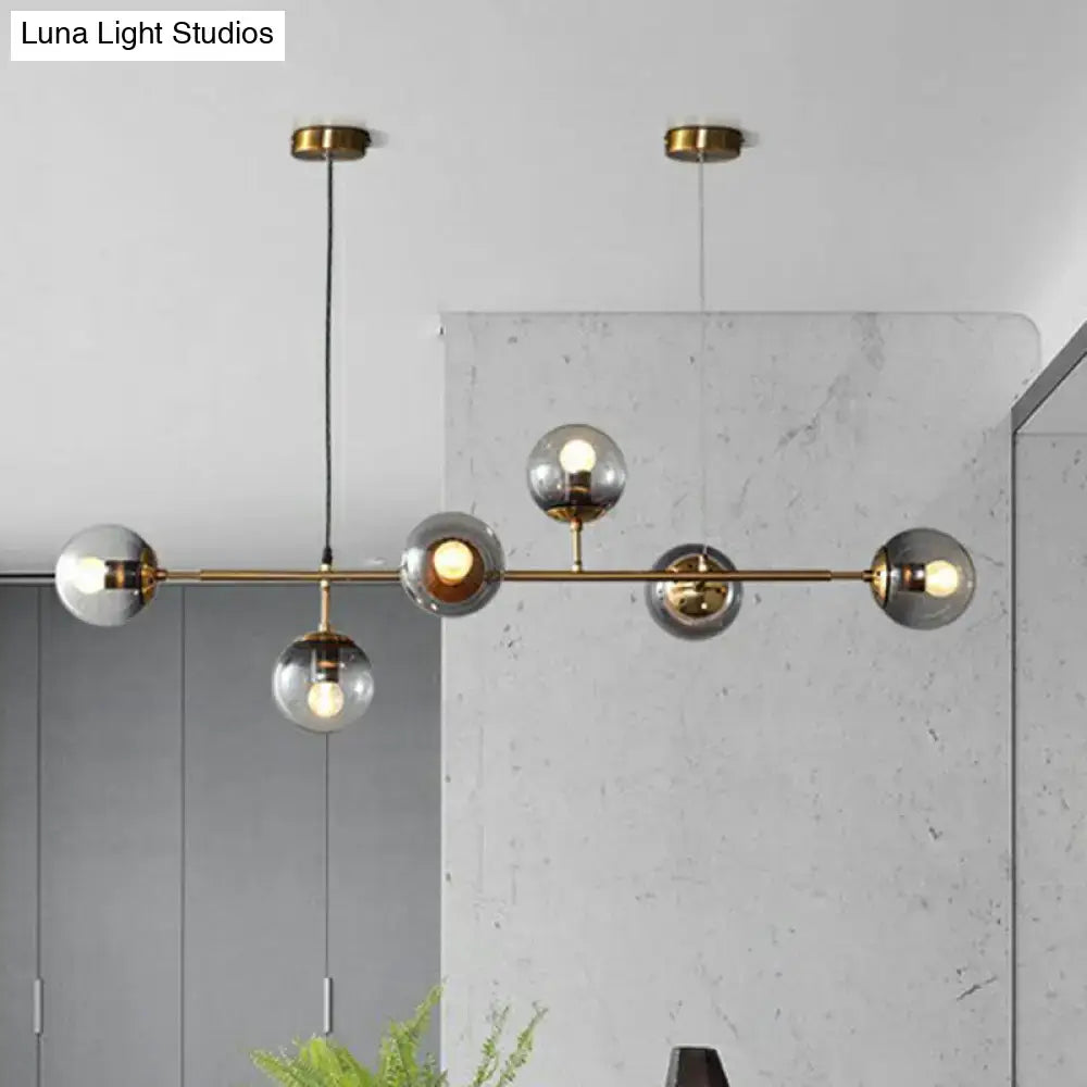Modern brass pendant light with smoke grey glass globe shades and brass finish ideal for restaurants and islands