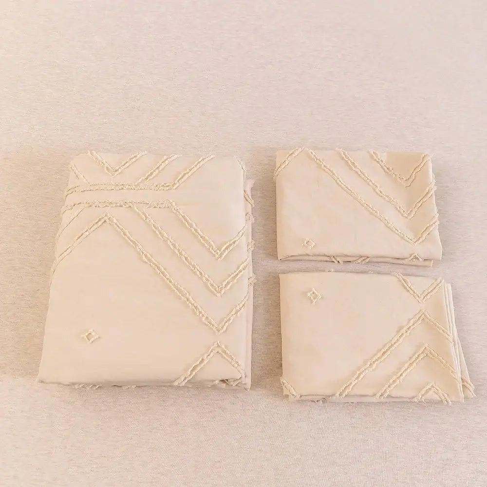 Cream-colored embroidered microfiber napkins with zigzag stitching and diamond motifs from a duvet cover set