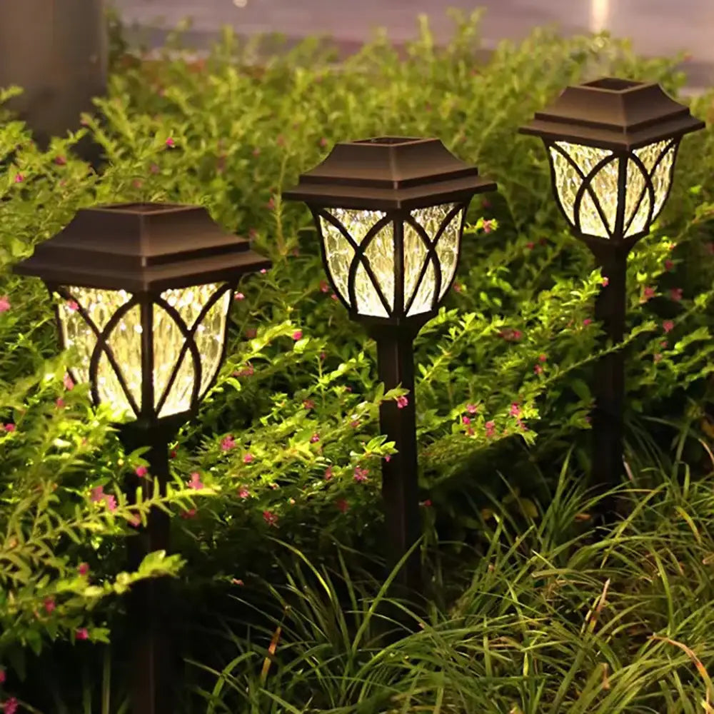 Three black decorbites™ solar lawn lights with textured glass panels and decorative lattice design for outdoor garden pathway