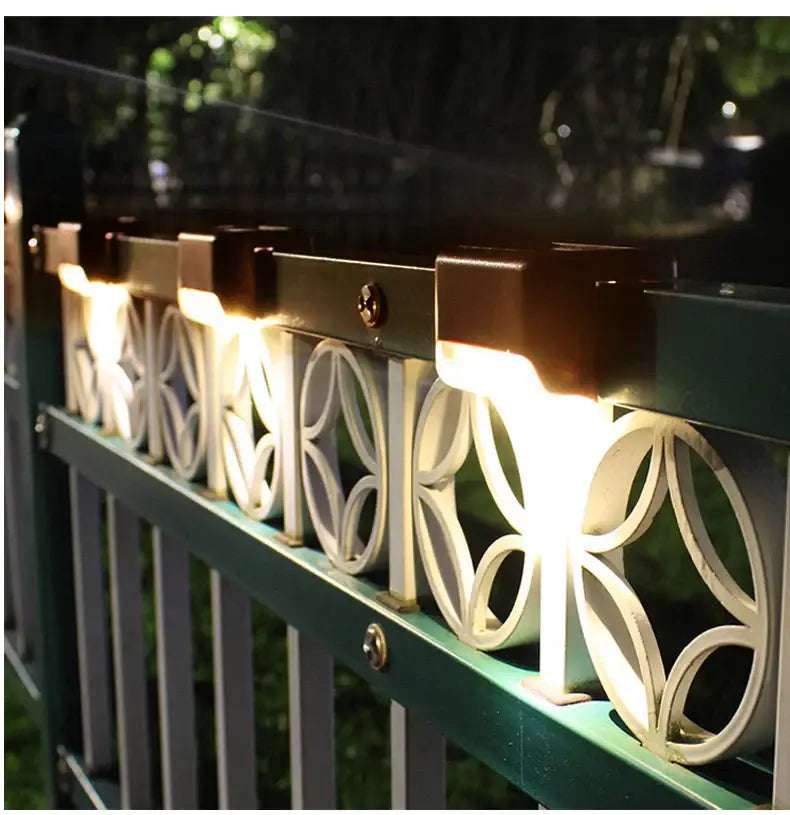 DecorBites solar led outdoor stair lights with warm white LEDs in sleek black housing mounted on green metal fence