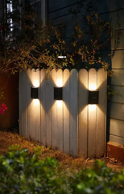 Decorbites solar led outdoor wall light with black lamp beads illuminating a weathered white wooden fence