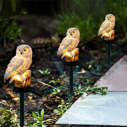 White owl garden light with glowing yellow eyes and textured feathers on black stakes for solar outdoor use