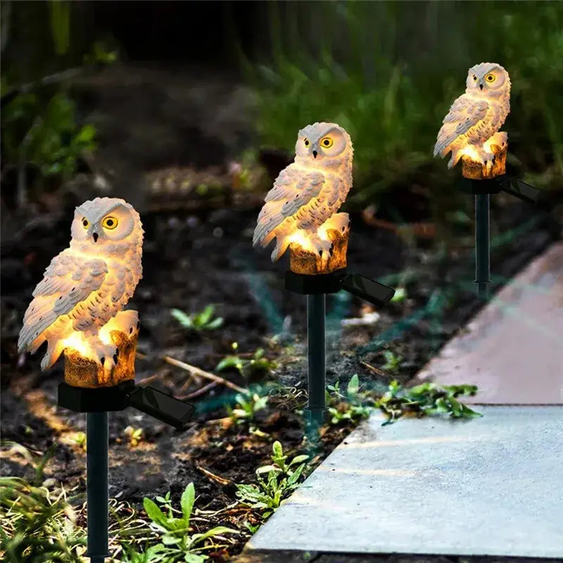 White owl garden light with glowing yellow eyes and textured feathers on black stakes for solar outdoor use