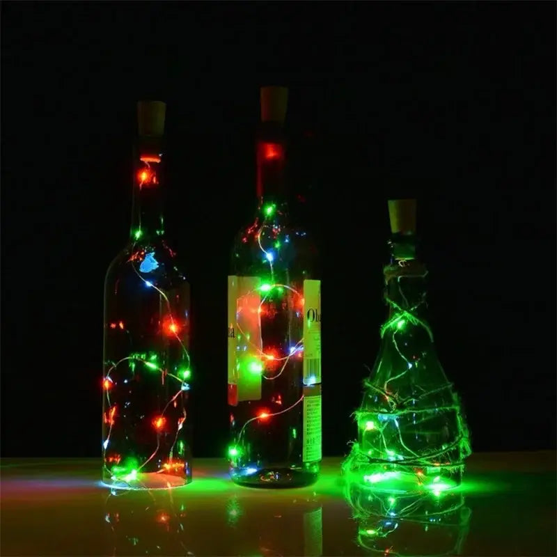 Three glass wine bottles with corks illuminated by red green and blue led solar wine bottle fairy lights for decor