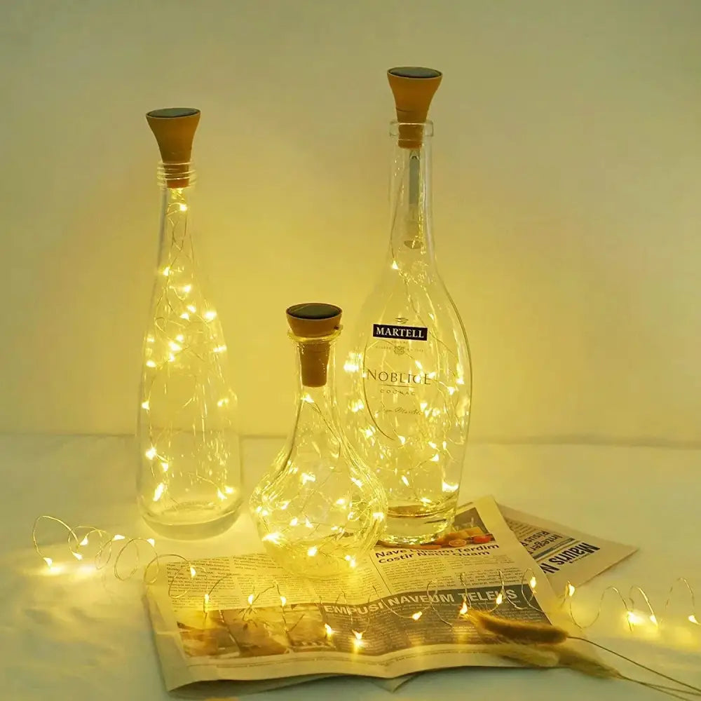 Three clear glass solar wine bottles with corks containing warm white led fairy lights for home decoration