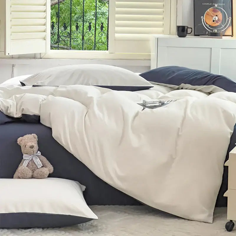 Cream-colored satin duvet cover with subtle sheen paired with navy blue solid color brush fabric pillowcases
