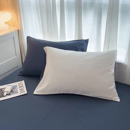 Cream-colored satin pillowcase with a glossy finish on dark blue brush fabric solid color duvet cover set by decorbites